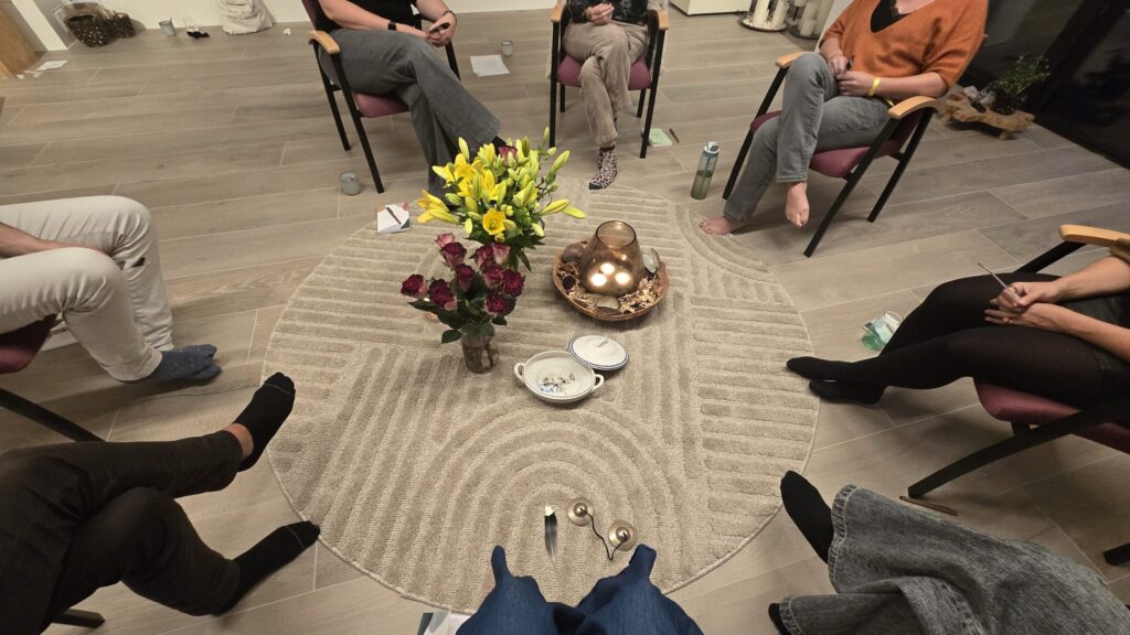 Cirkel van stoelen met bloemen in het midden, opstelling in Oase41